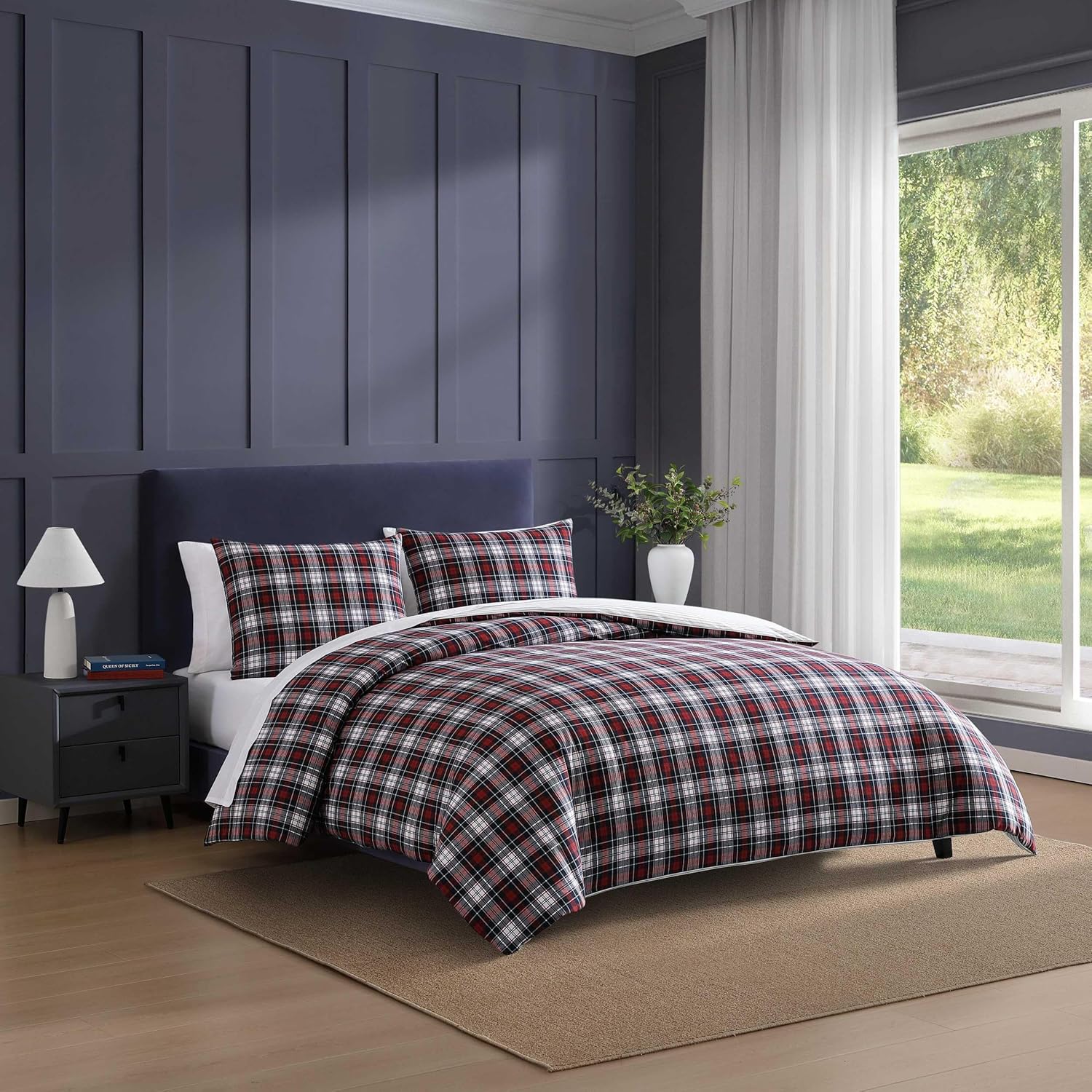 A made bed dressed in a Tommy Hilfiger tartan red comforter set with matching shams